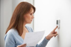 Woman Adjusting Thermostat to heat pump